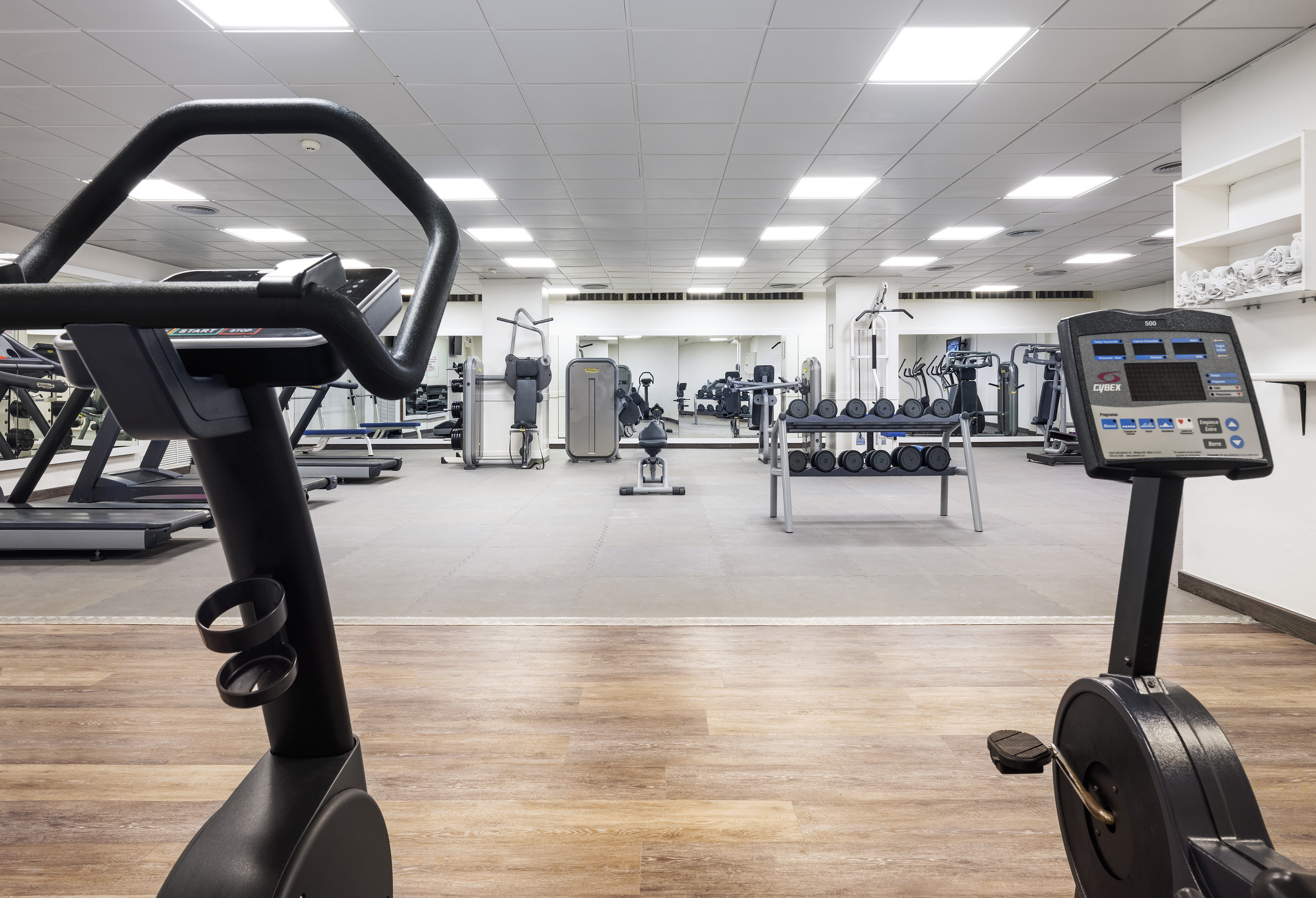 Spacious gym with exercise bikes, treadmills, weight machines, and dumbbells.