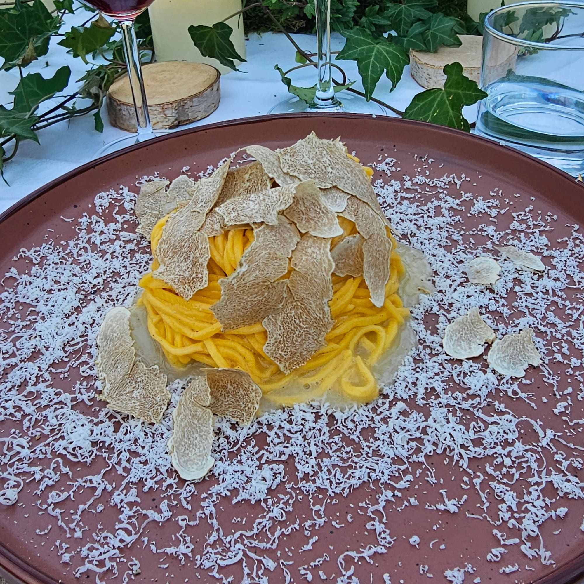 Yellow spaghetti with white truffle shavings and grated Parmesan cheese.