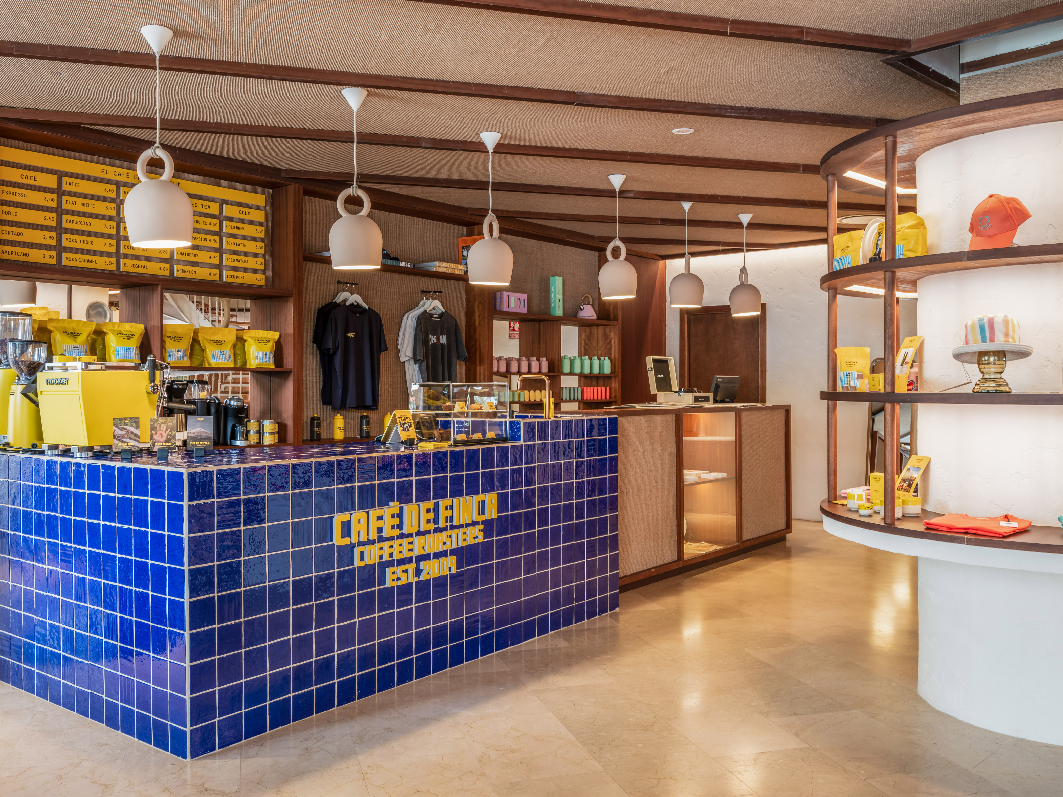 Cafe de Finca coffee shop interior with blue tiled counter, menu, and merchandise.
