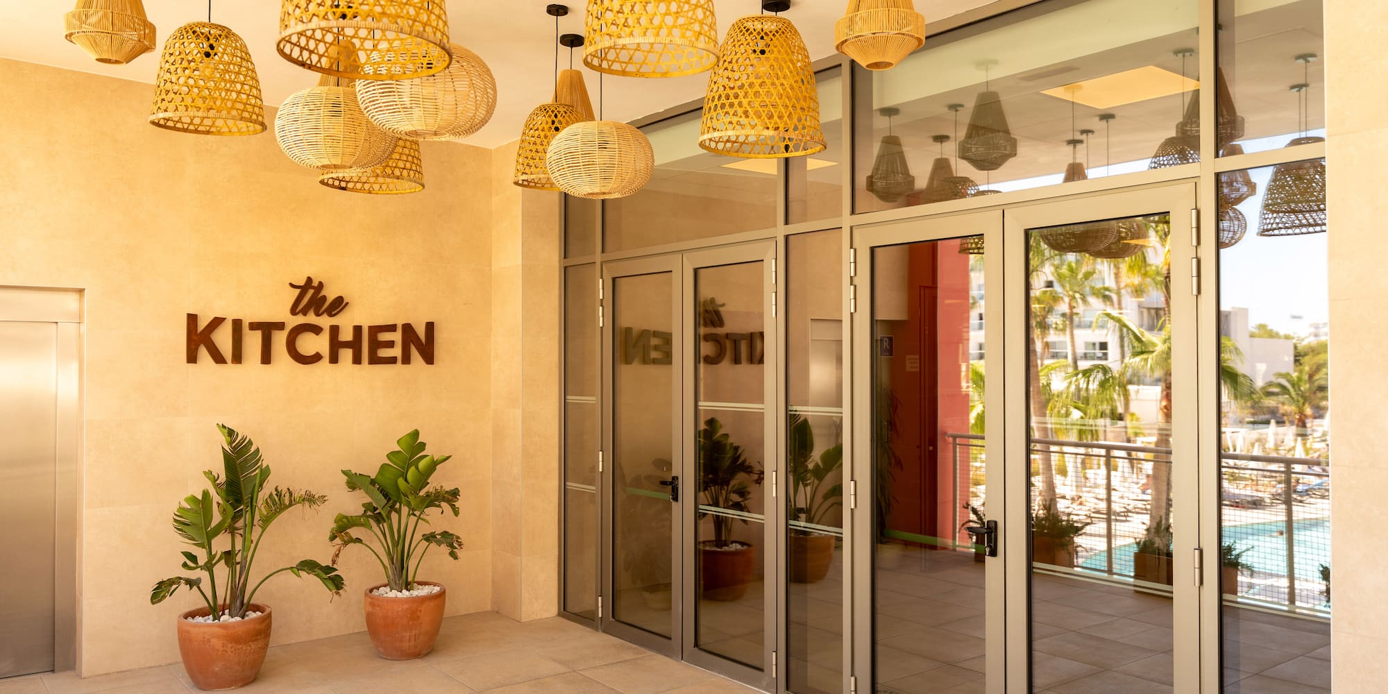 The Kitchen restaurant entrance with woven lights and tropical plants.