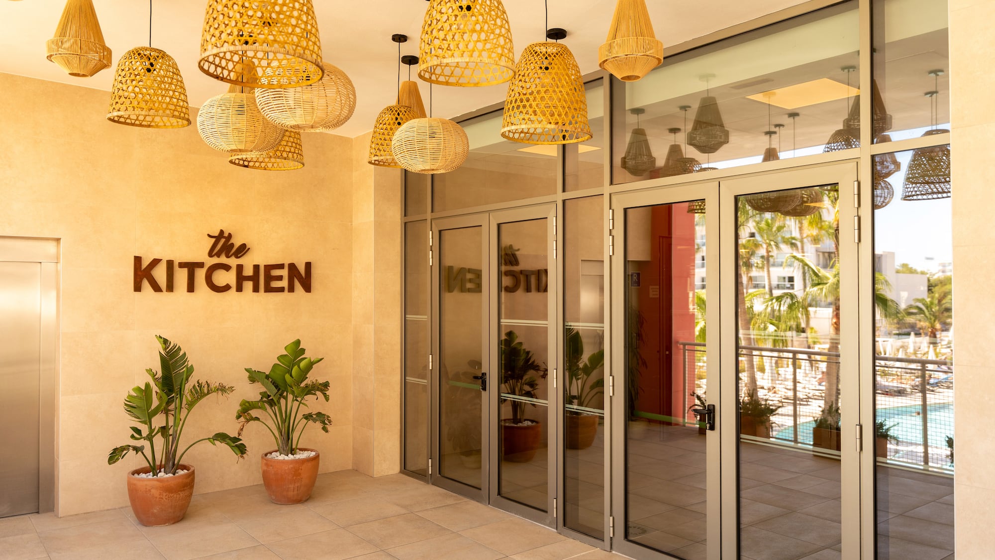 The Kitchen restaurant entrance with woven lights and tropical plants.