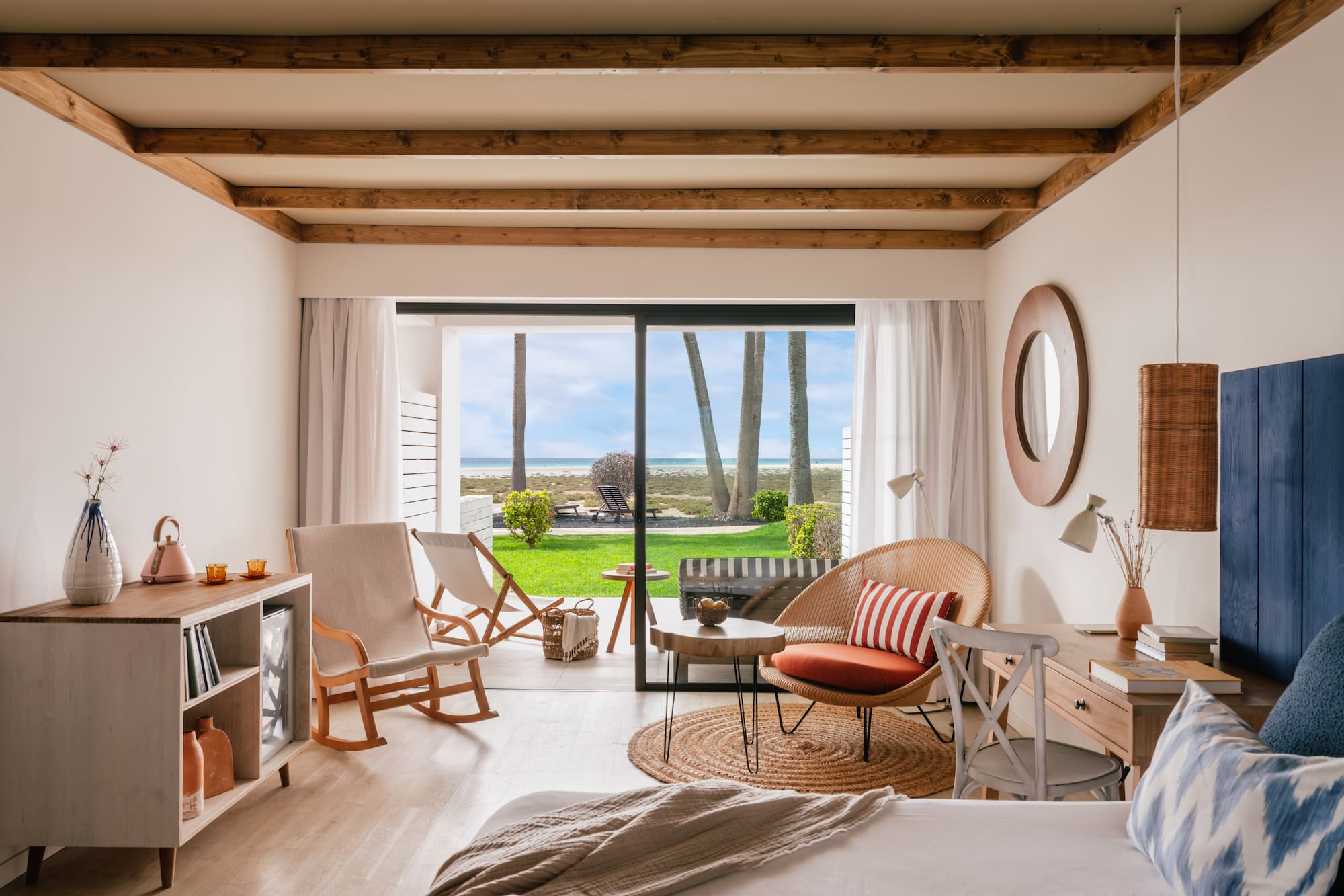 Interior de habitación costera con vista al mar, palmeras y patio.