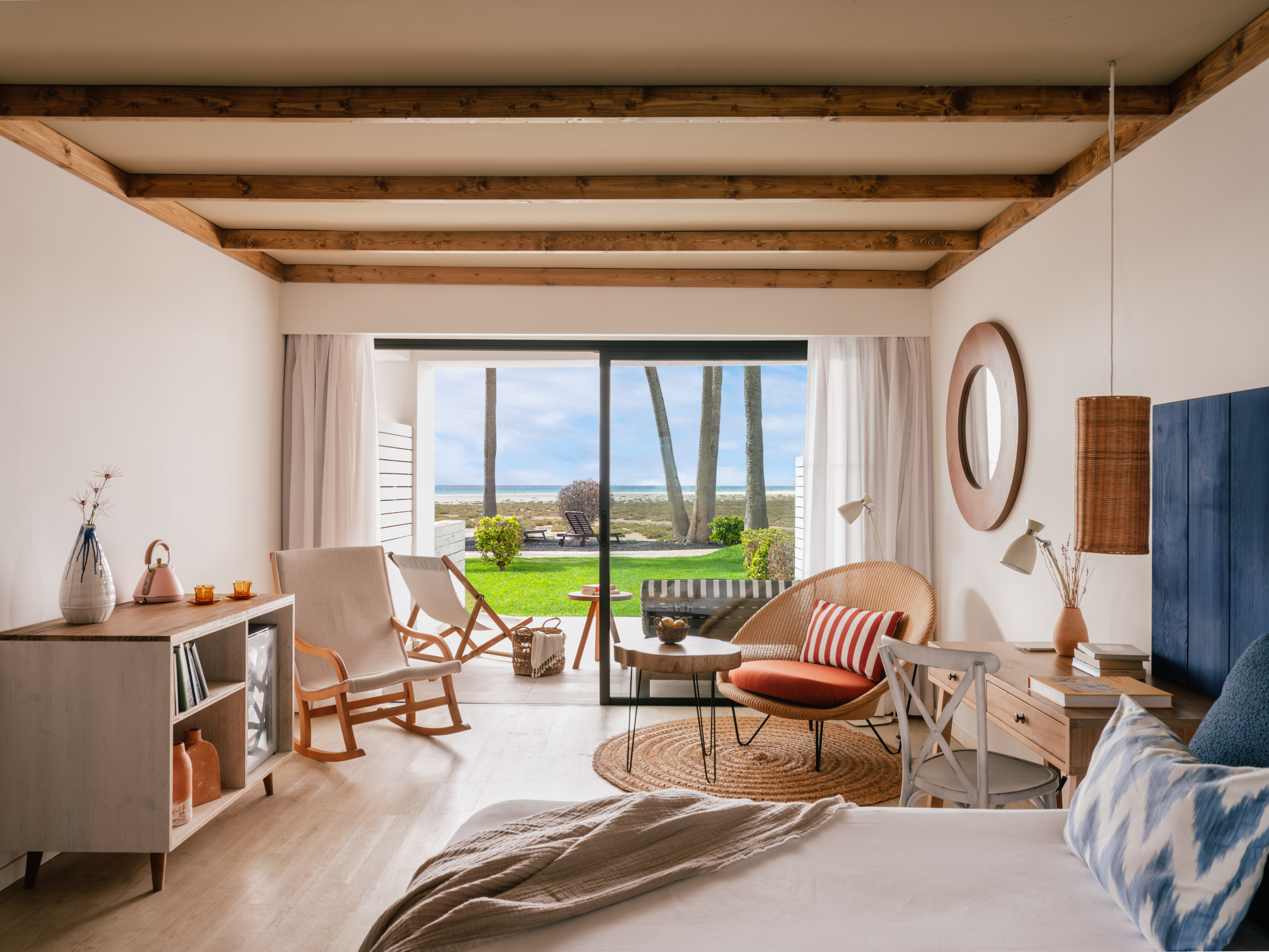 Interior de habitación costera con vista al mar, palmeras y patio.