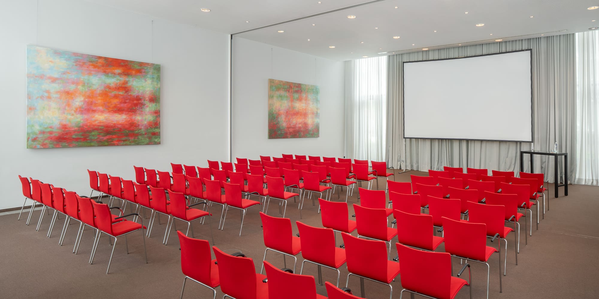 a room with red chairs and a projector screen