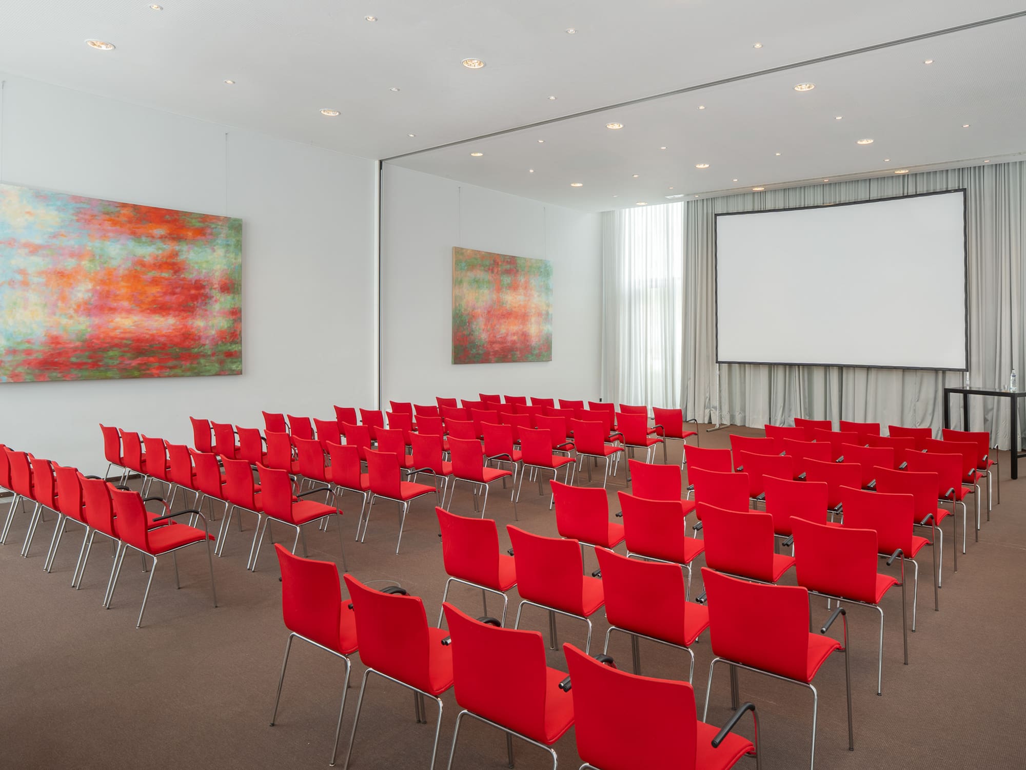 a room with red chairs and a projector screen