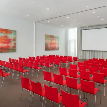 a room with red chairs and a projector screen