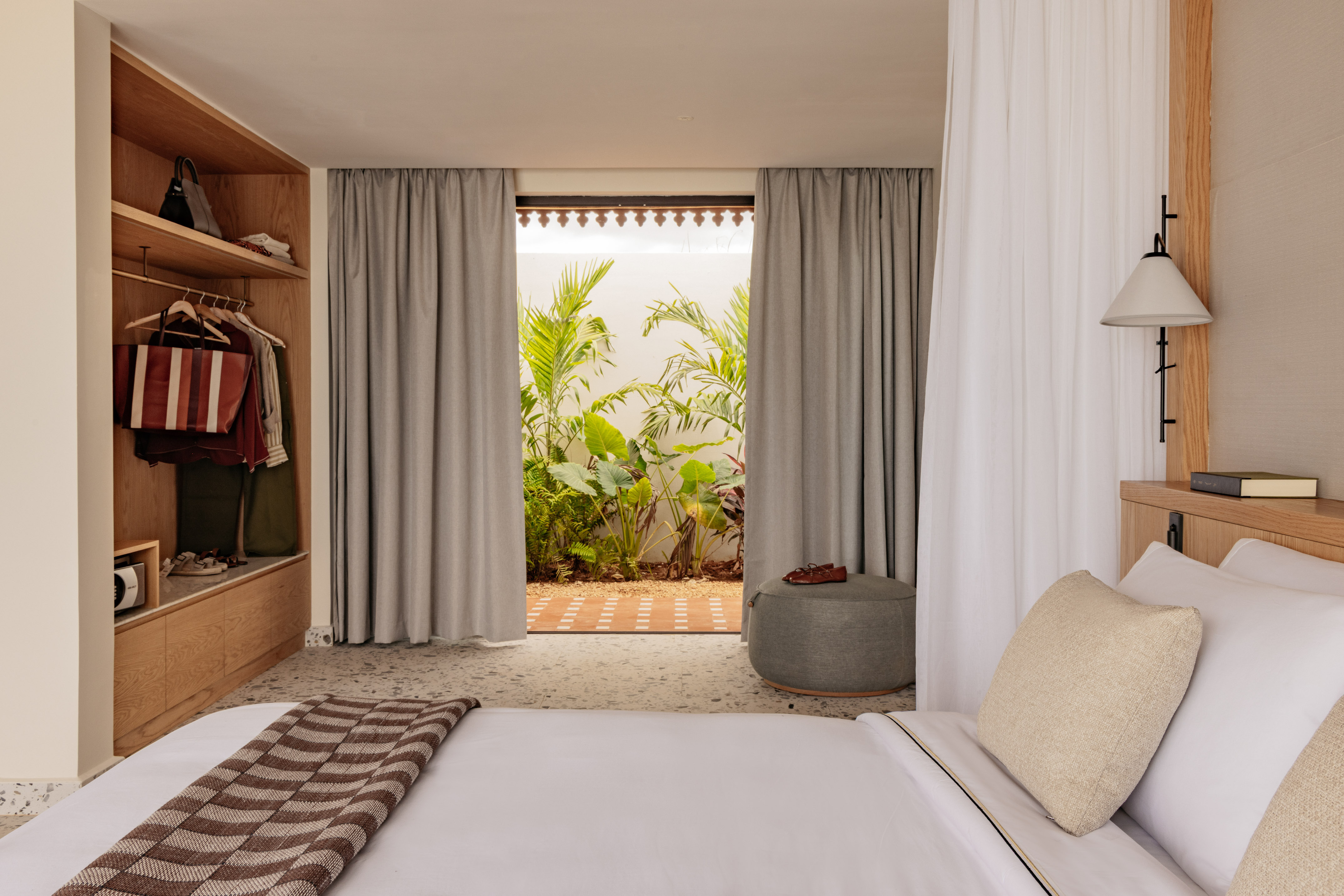 Modern tropical bedroom with white bed, open closet, and garden view.