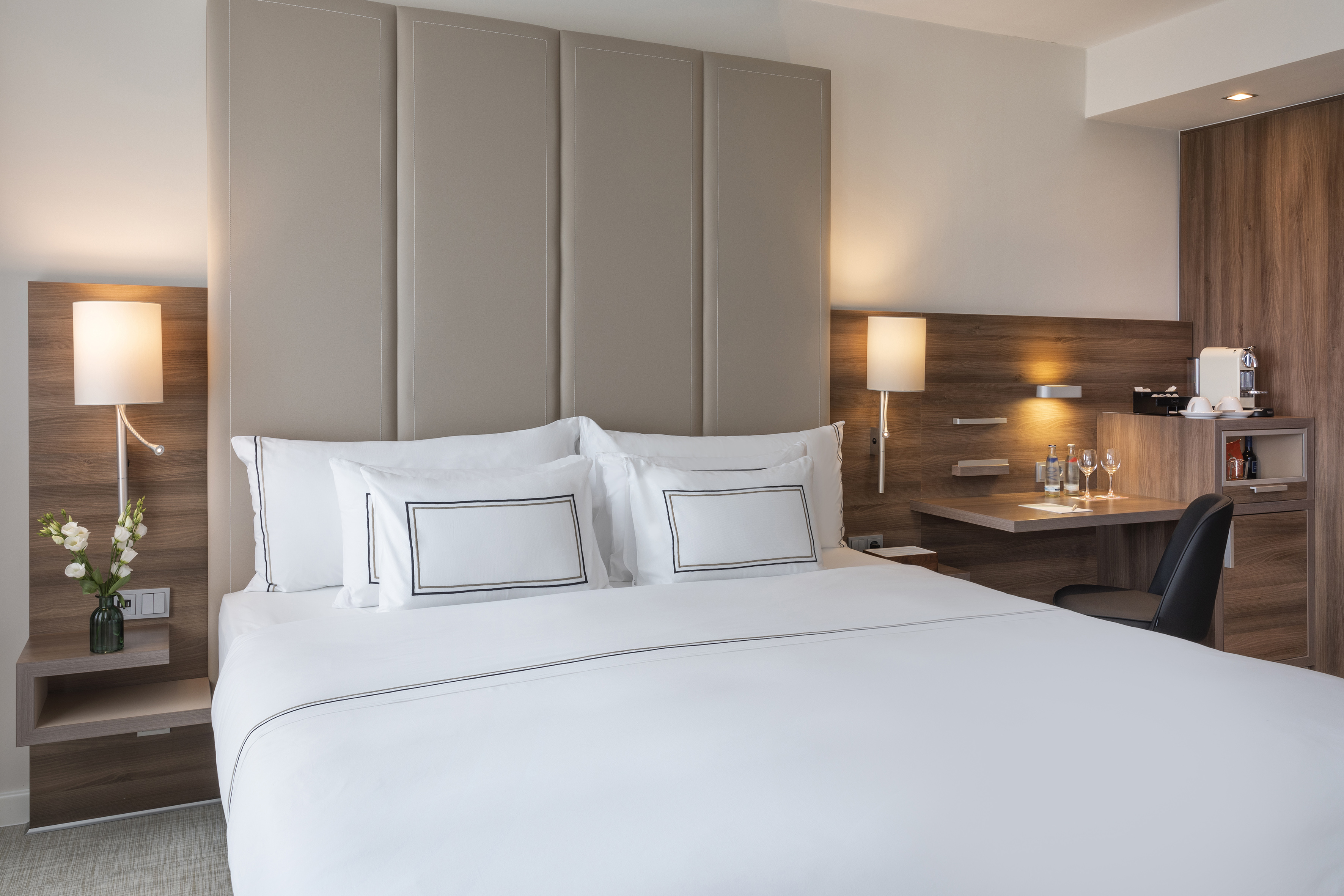 Modern hotel room with king bed, upholstered headboard, and workspace.