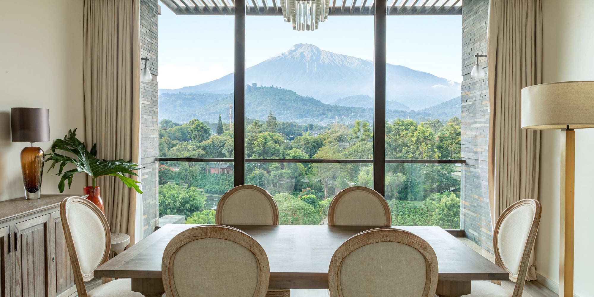 a dining room with a table and chairs and a mountain in the background