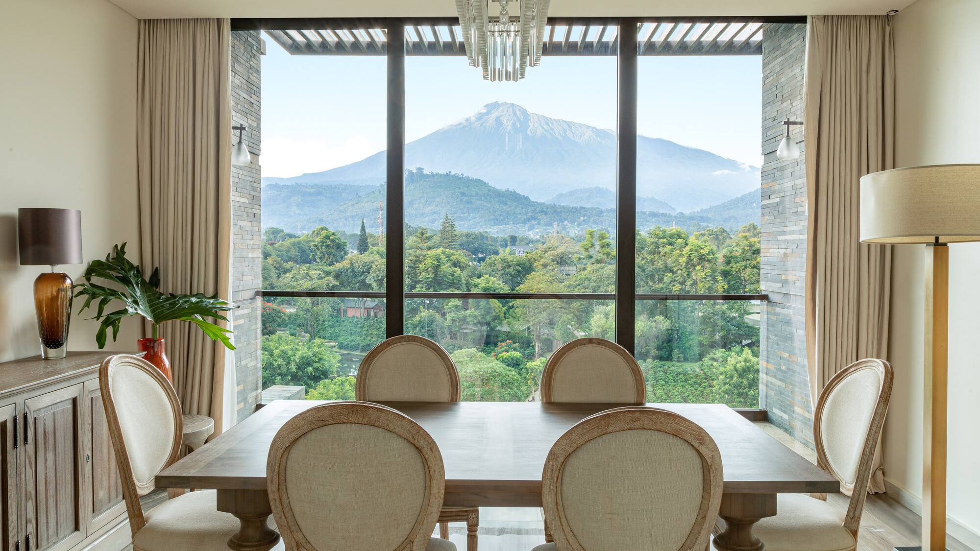 a dining room with a table and chairs and a mountain in the background