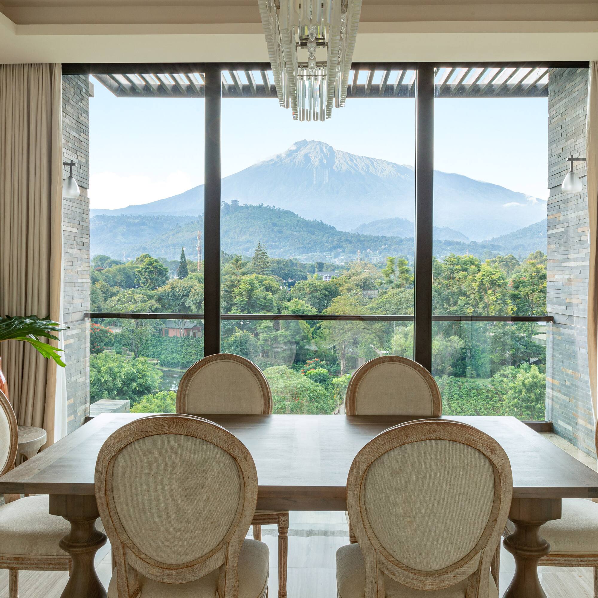 a dining room with a table and chairs and a mountain in the background