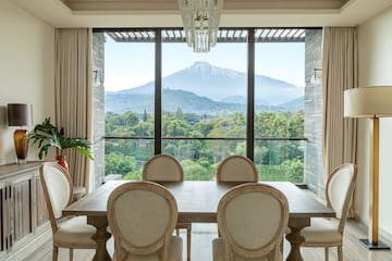 a dining room with a table and chairs and a mountain in the background