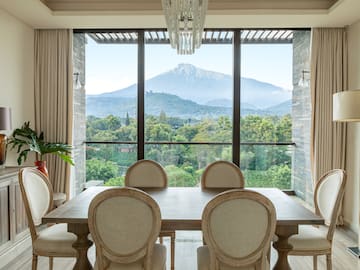 a dining room with a table and chairs and a mountain in the background