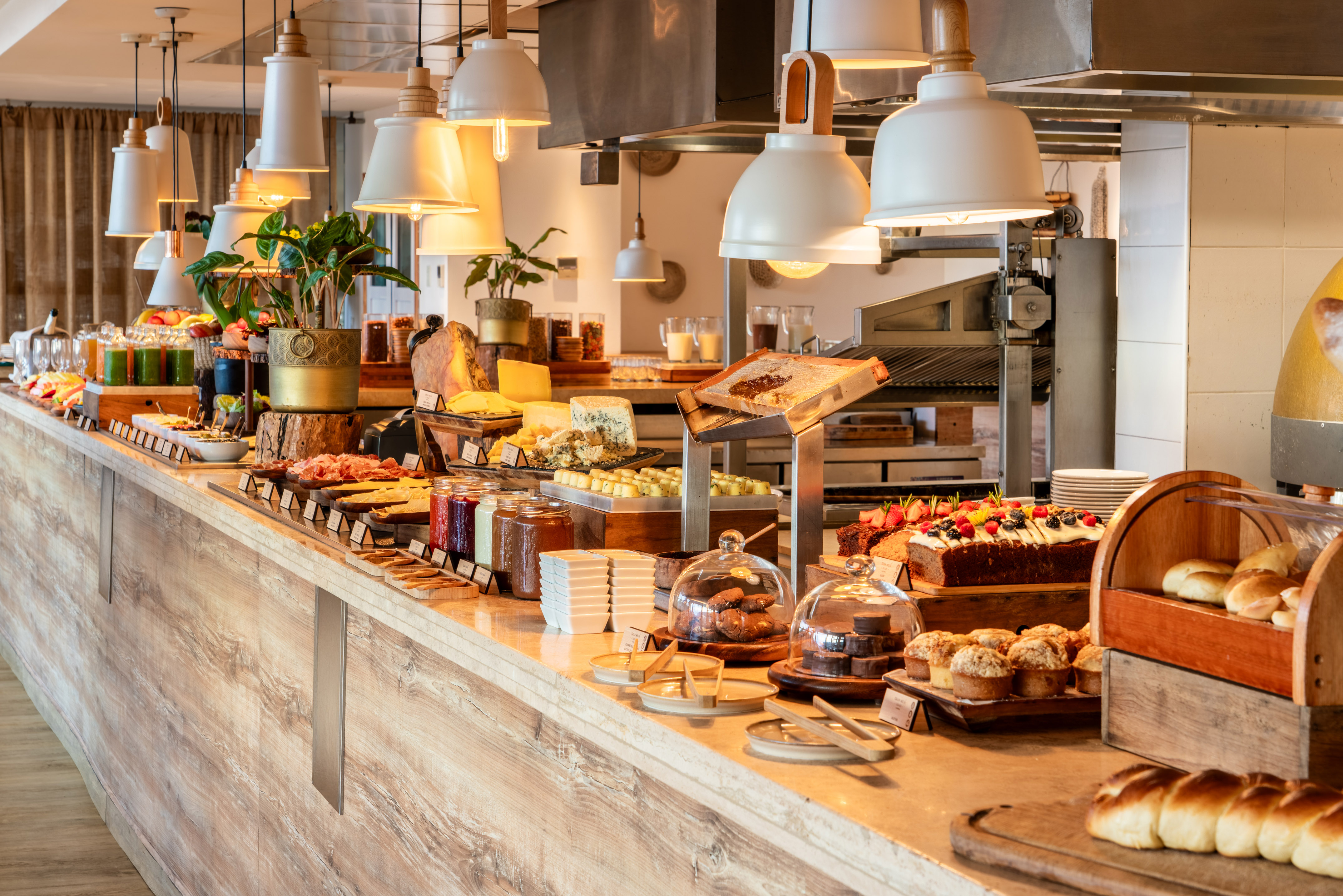 Cheeses, pastries, cold cuts, and juices on a hotel breakfast buffet.
