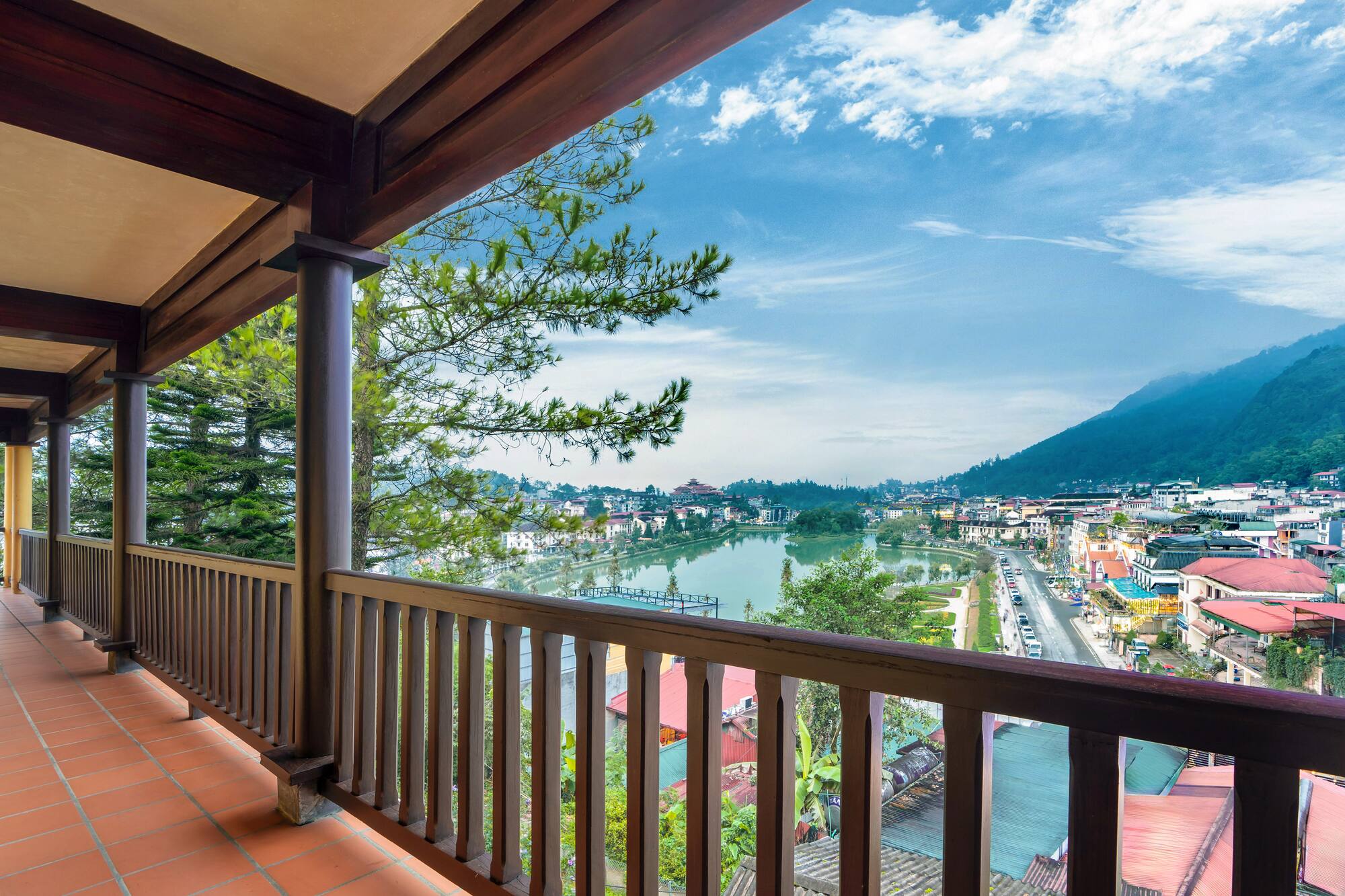 Wooden balcony view of a town with a lake and mountains.