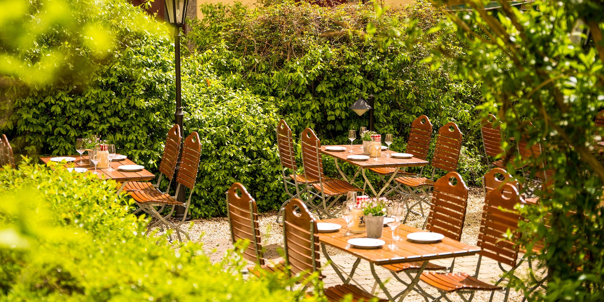 a table and chairs outside with bushes and a building