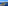 Helicopter flying above a green coastal island with yachts in a blue ocean.