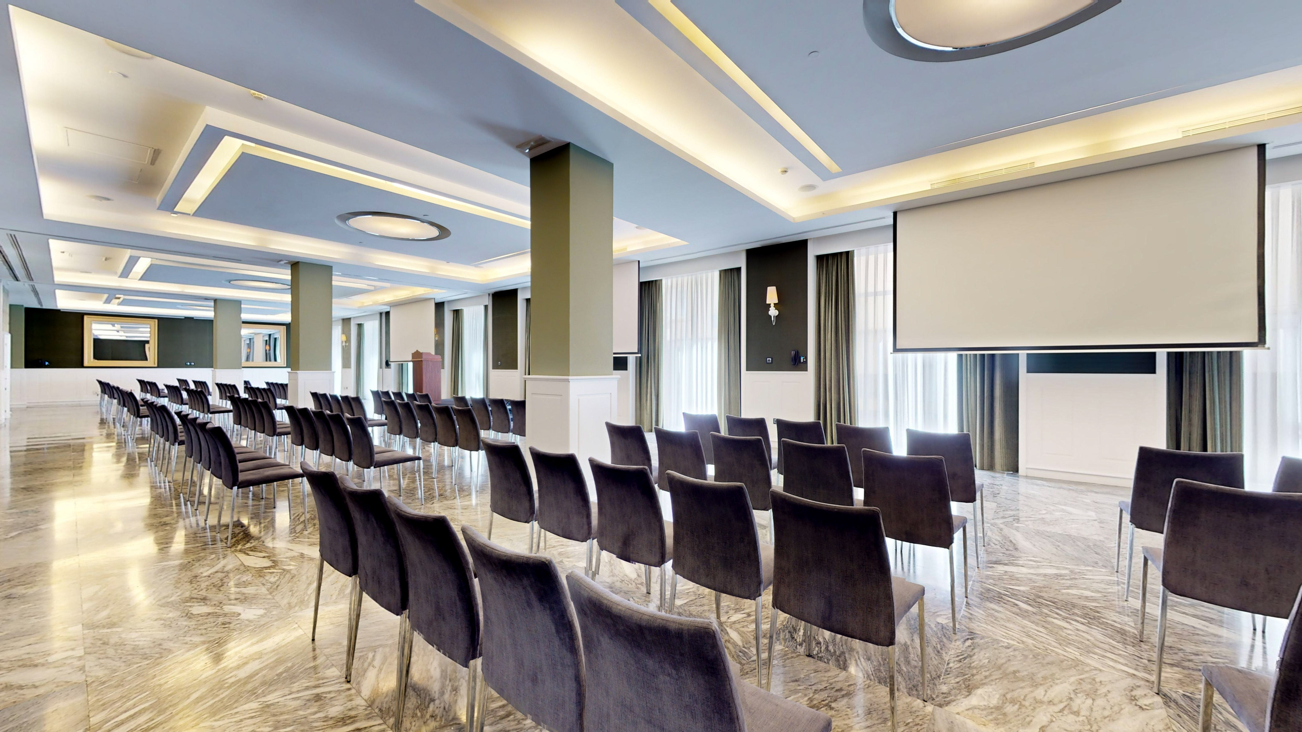 Modern conference room with grey chairs, marble floor, and presentation screen.