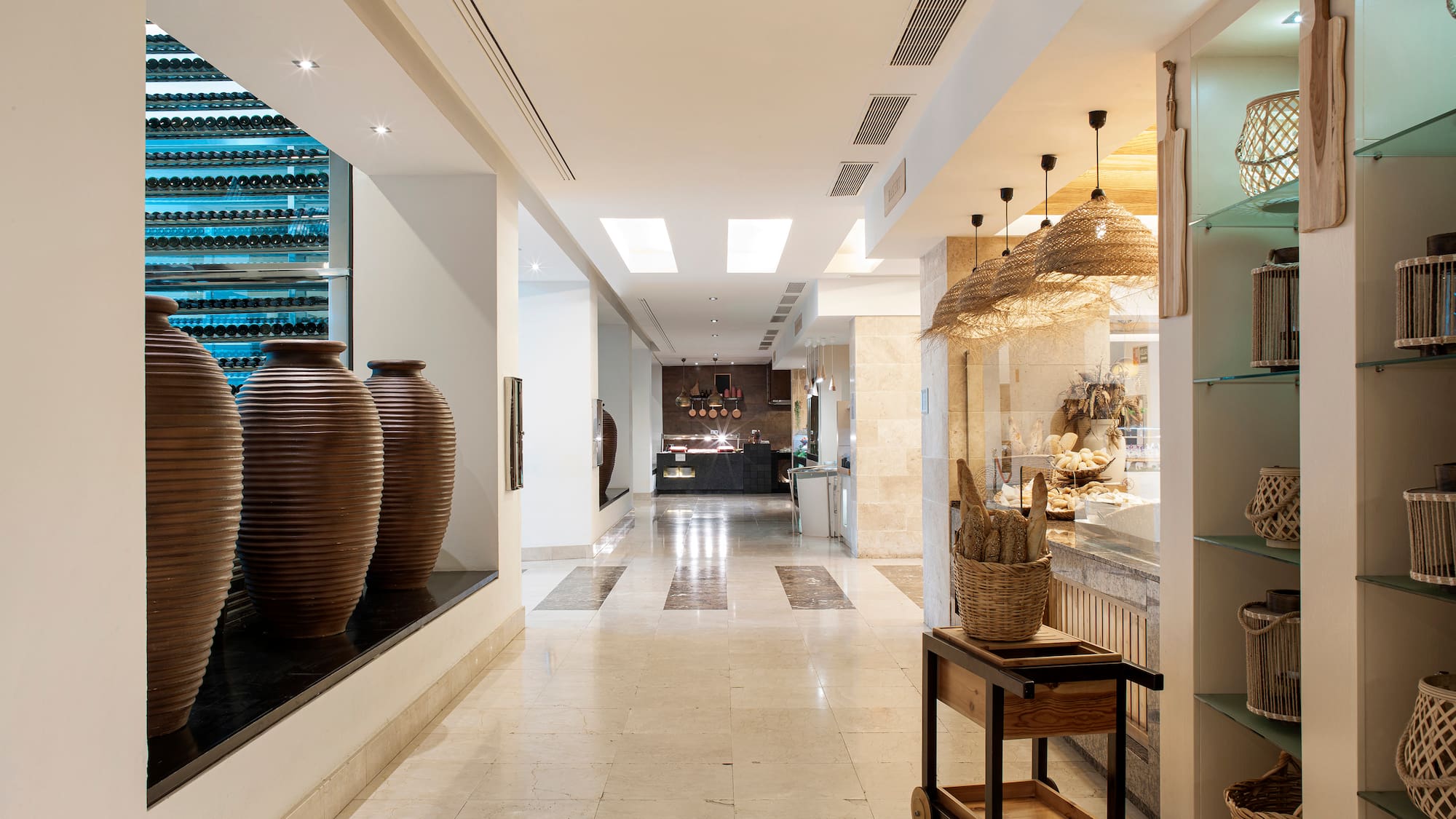 Modern hotel corridor with wine cellar, bakery display, and woven lighting.