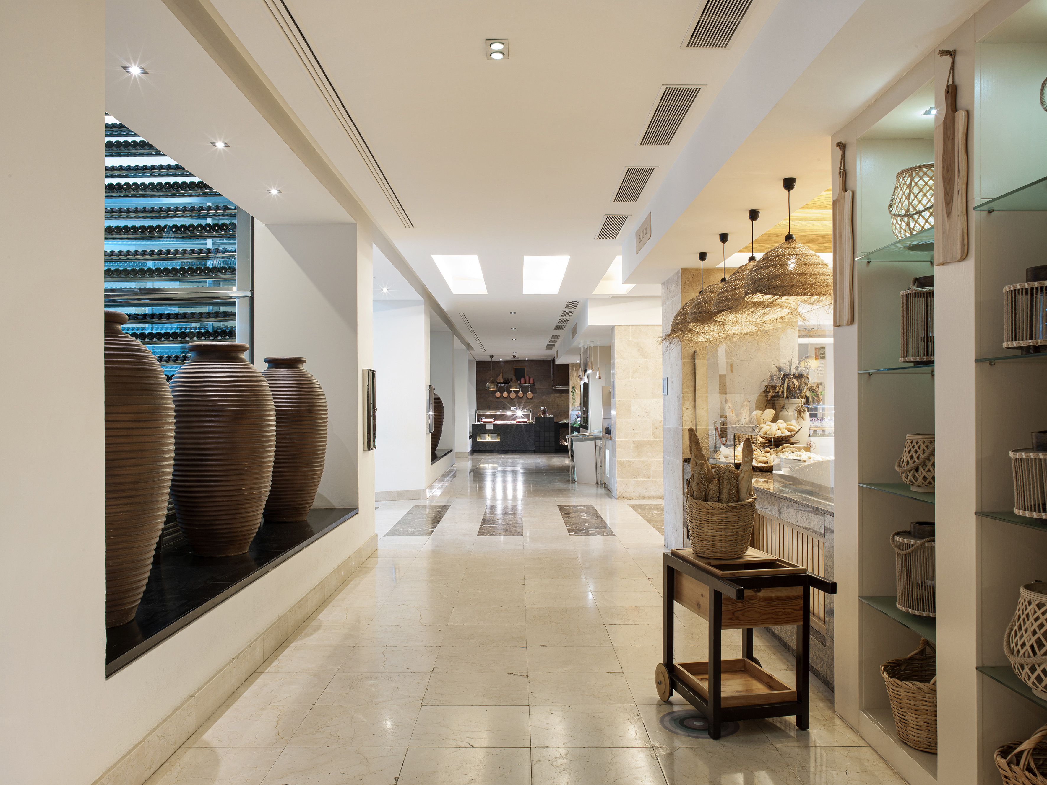 Modern hotel corridor with wine cellar, bakery display, and woven lighting.