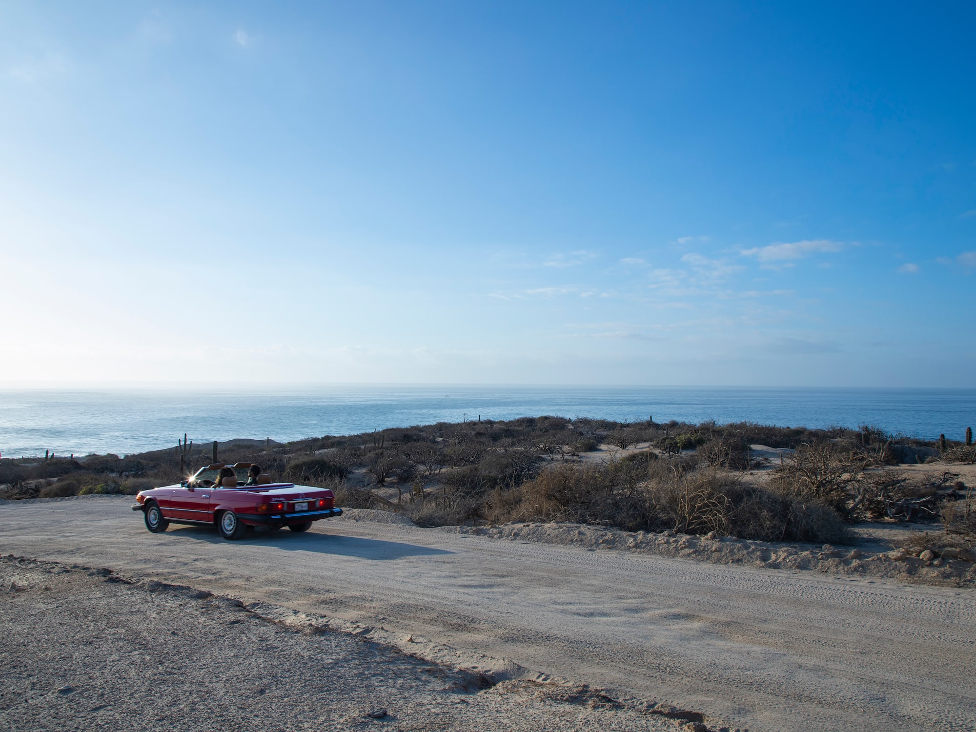 a car parked on a dirt road near water