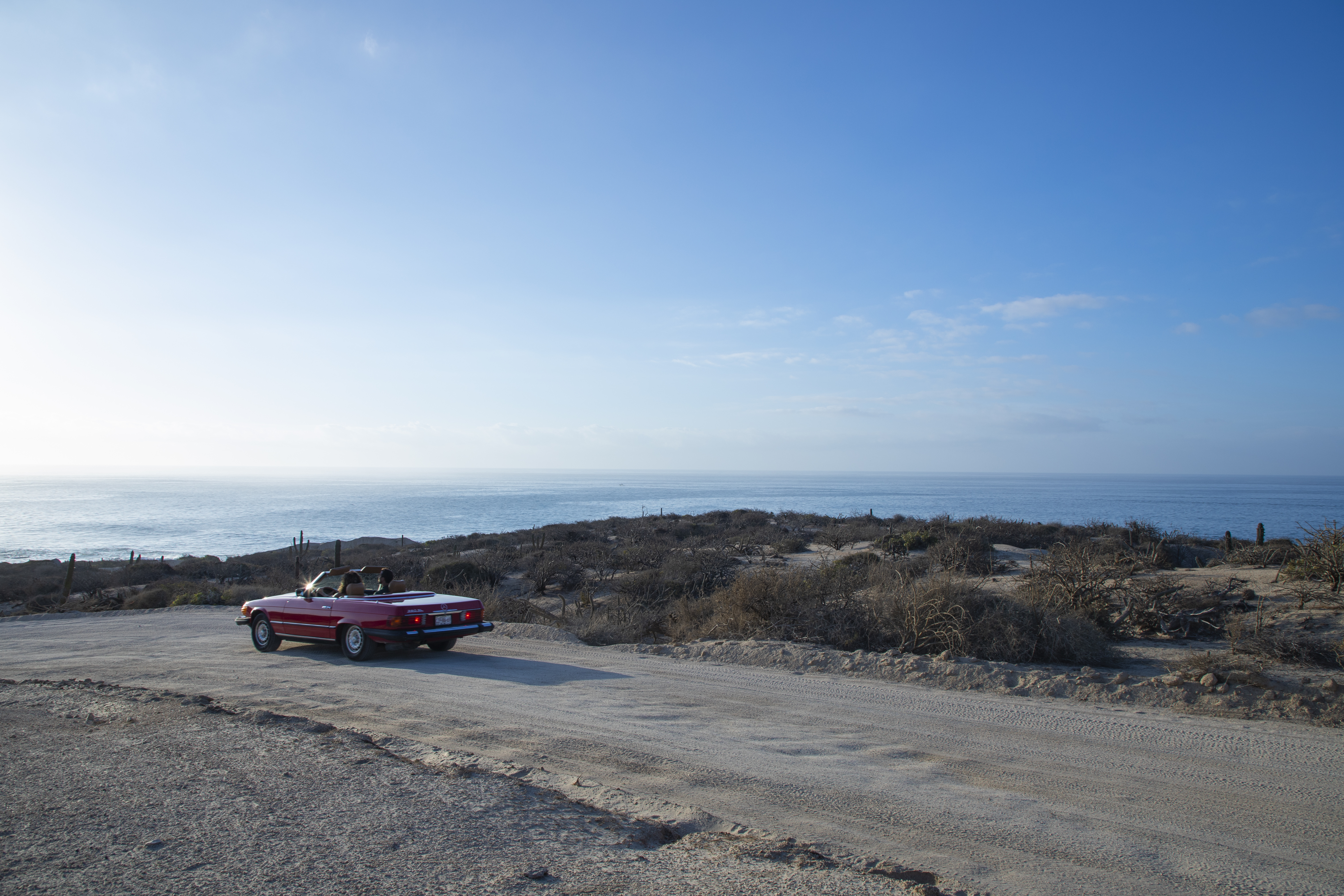 a car parked on a dirt road near water