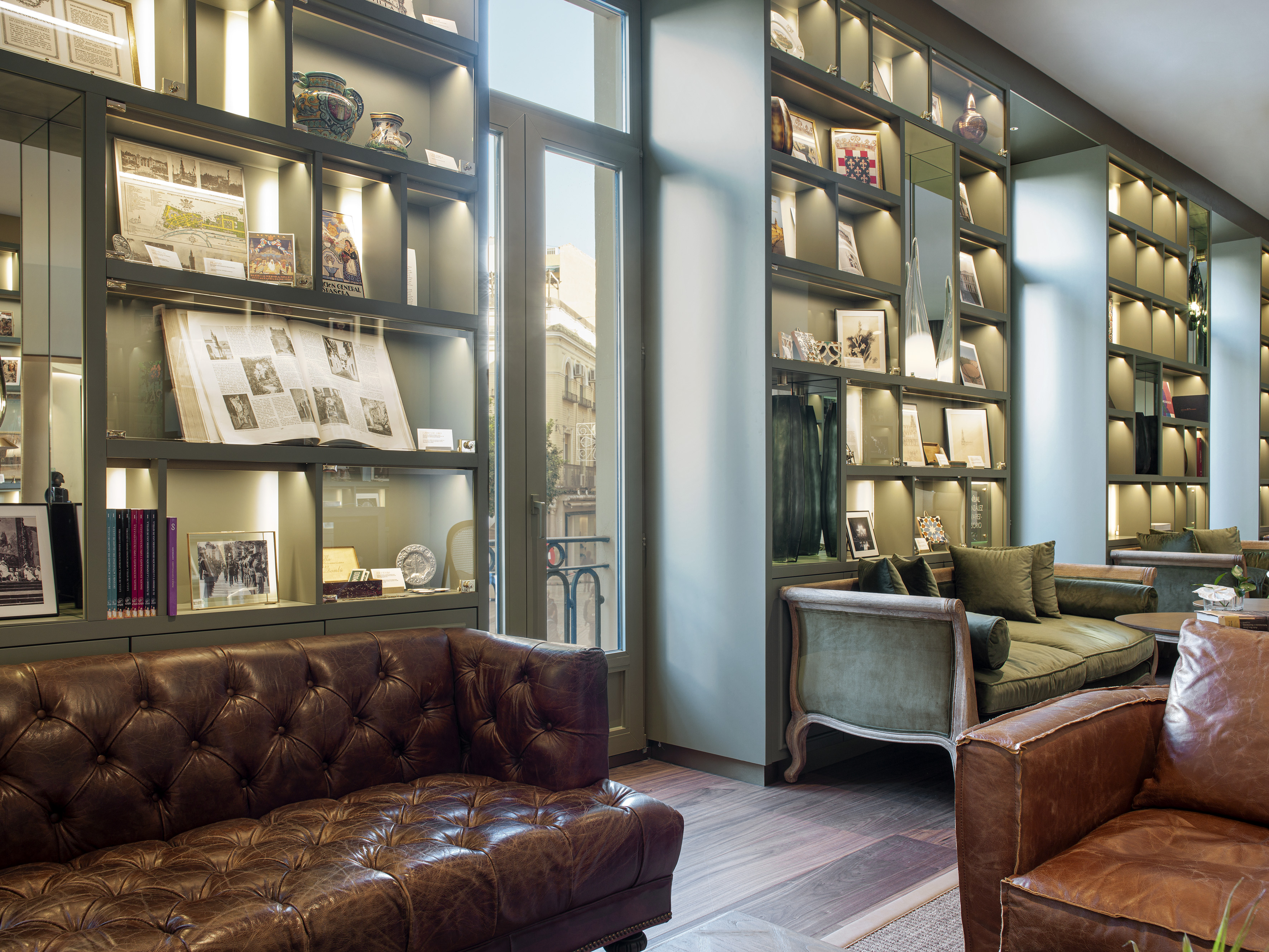 Elegant library lounge with leather sofas, green seating, and historic display cases.
