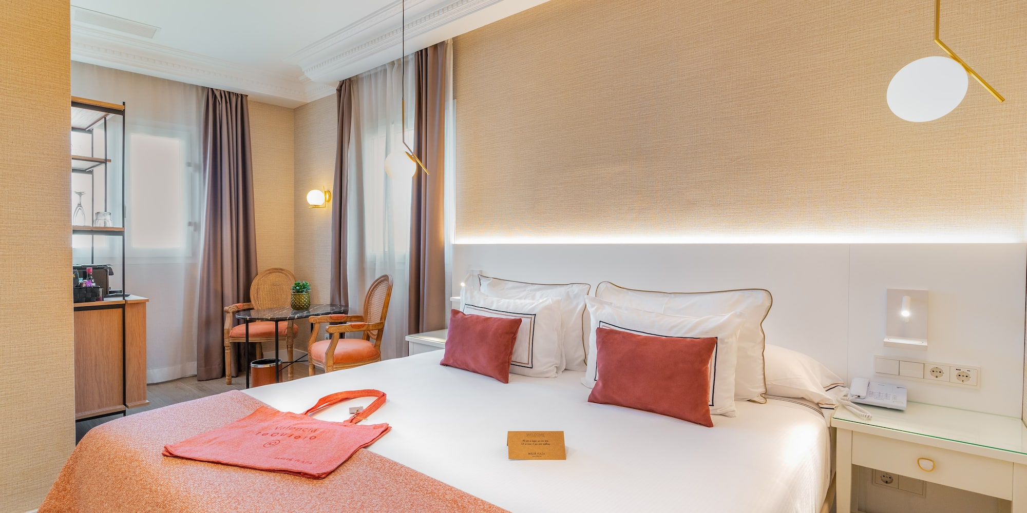 a bed with a red blanket and a table and chairs