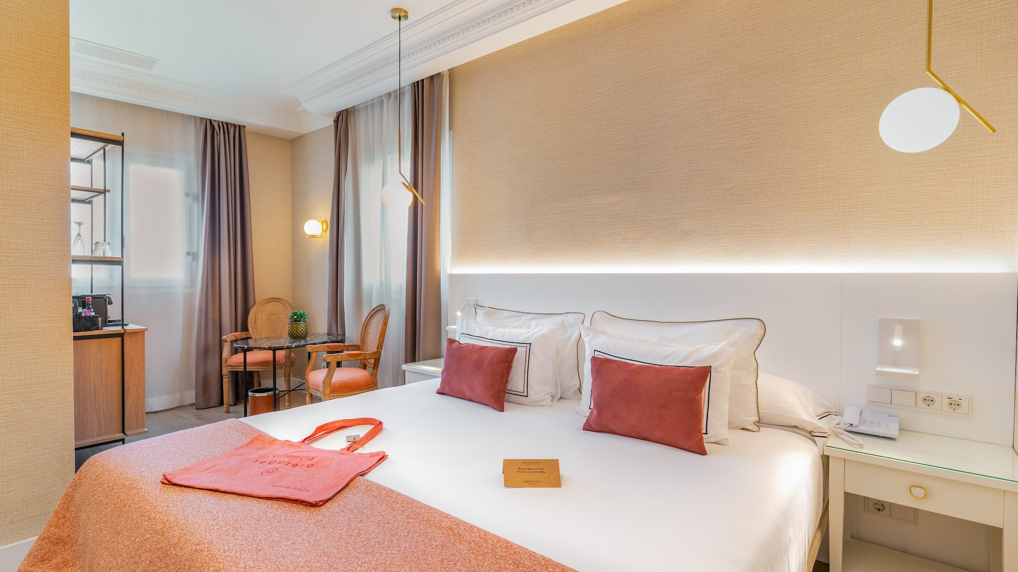 a bed with a red blanket and a table and chairs