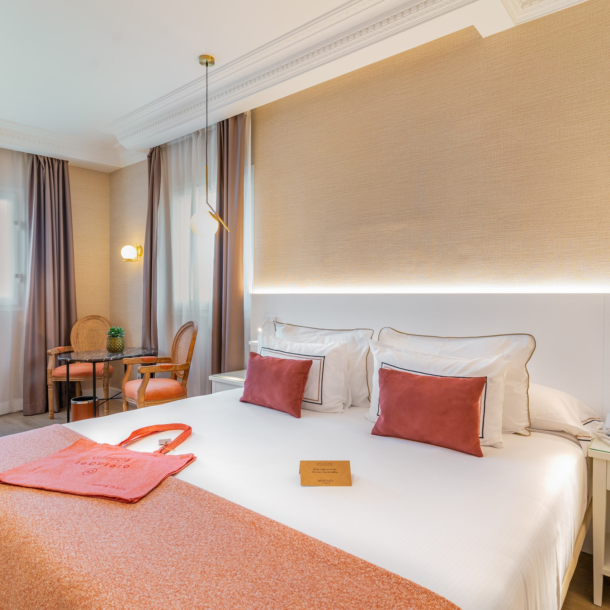 a bed with a red blanket and a table and chairs