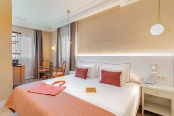 a bed with a red blanket and a table and chairs