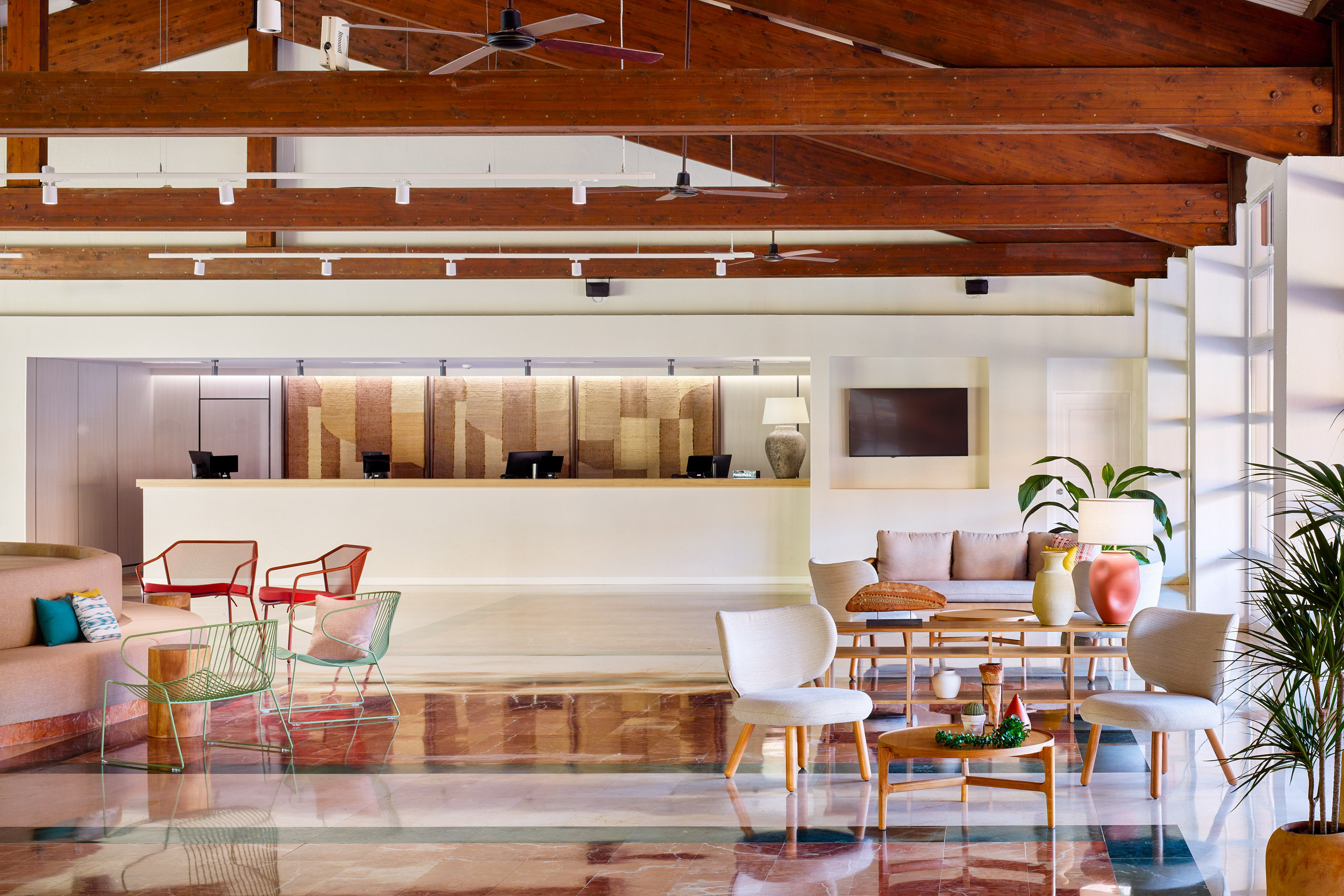 Resort hotel lobby with reception, wooden beams, and contemporary lounge seating.