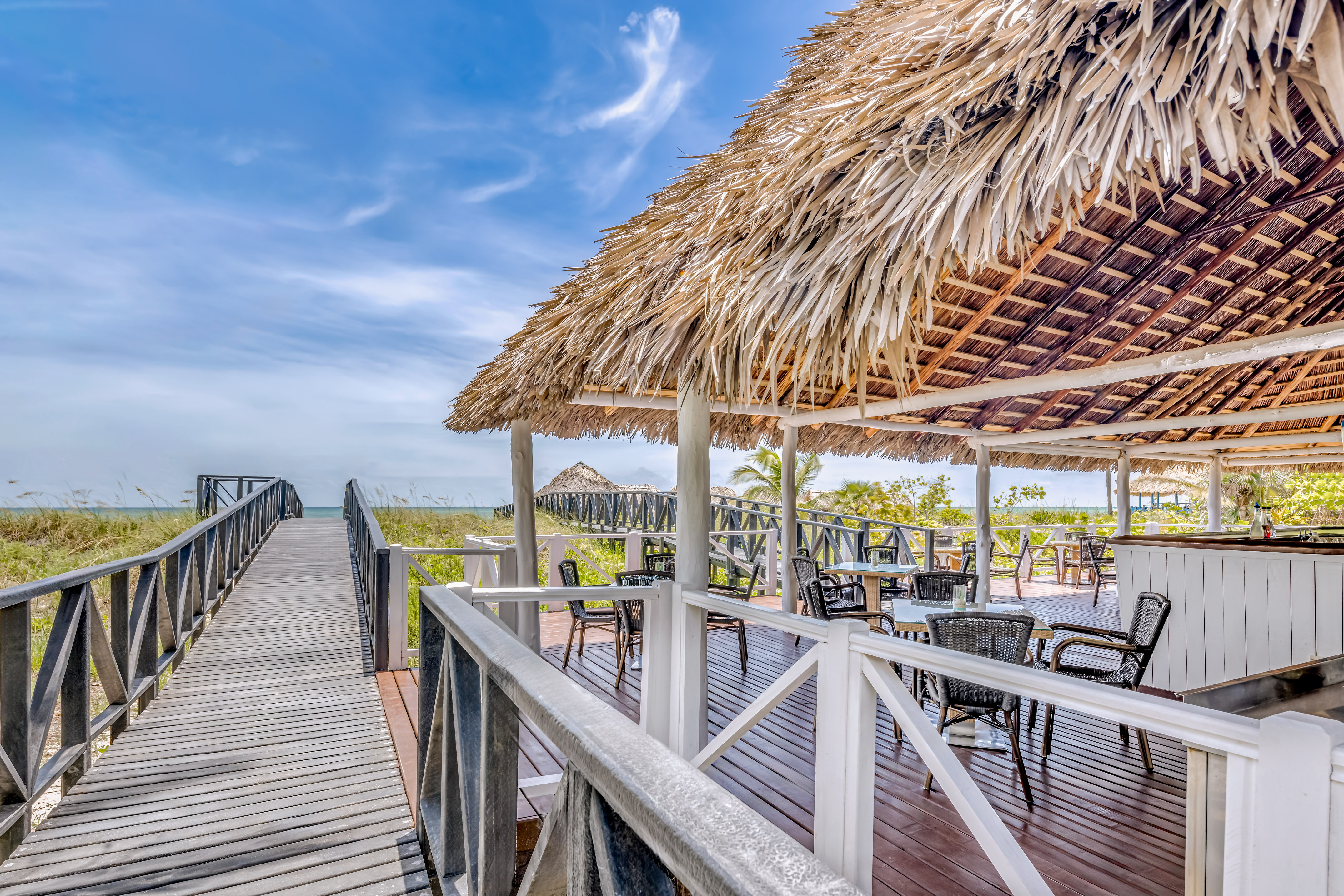 a deck with a thatched roof and chairs on it