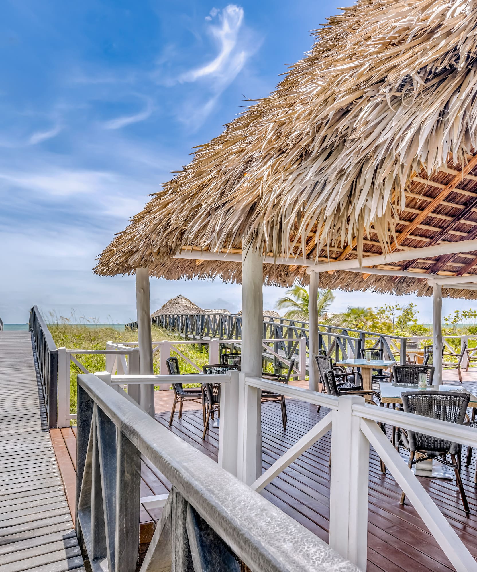 a deck with a thatched roof and chairs on it