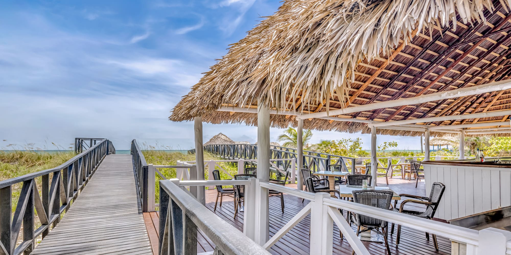 a deck with a thatched roof and chairs on it