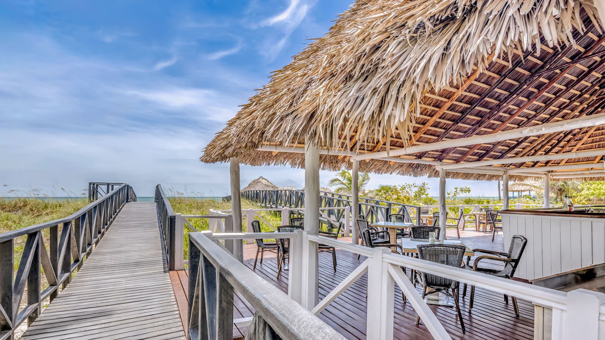 a deck with a thatched roof and chairs on it
