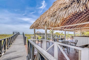 a deck with a thatched roof and chairs on it