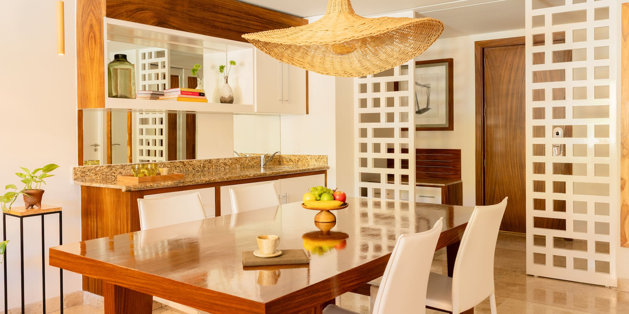 Modern dining room with wooden table, white chairs, and a wicker pendant light.
