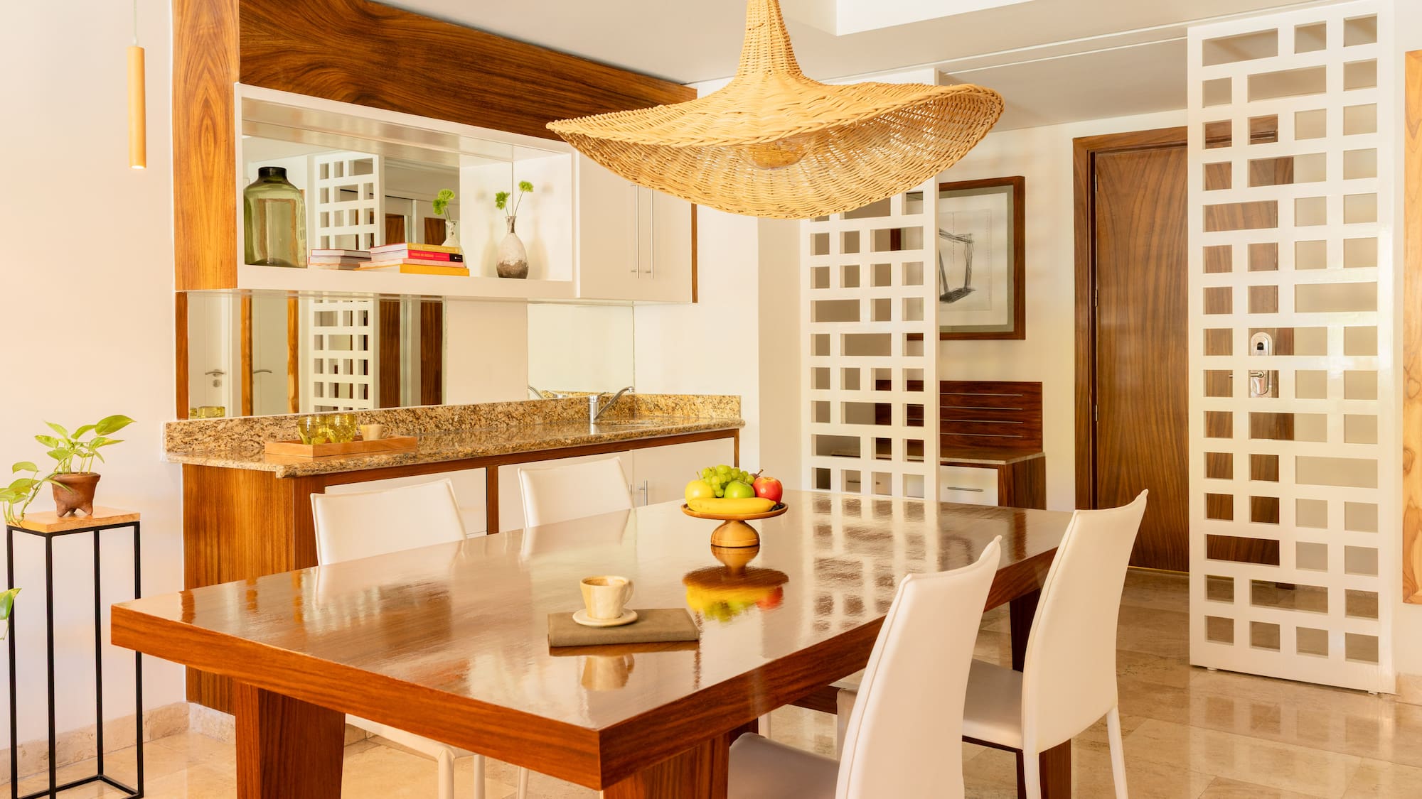 Modern dining room with wooden table, white chairs, and a wicker pendant light.