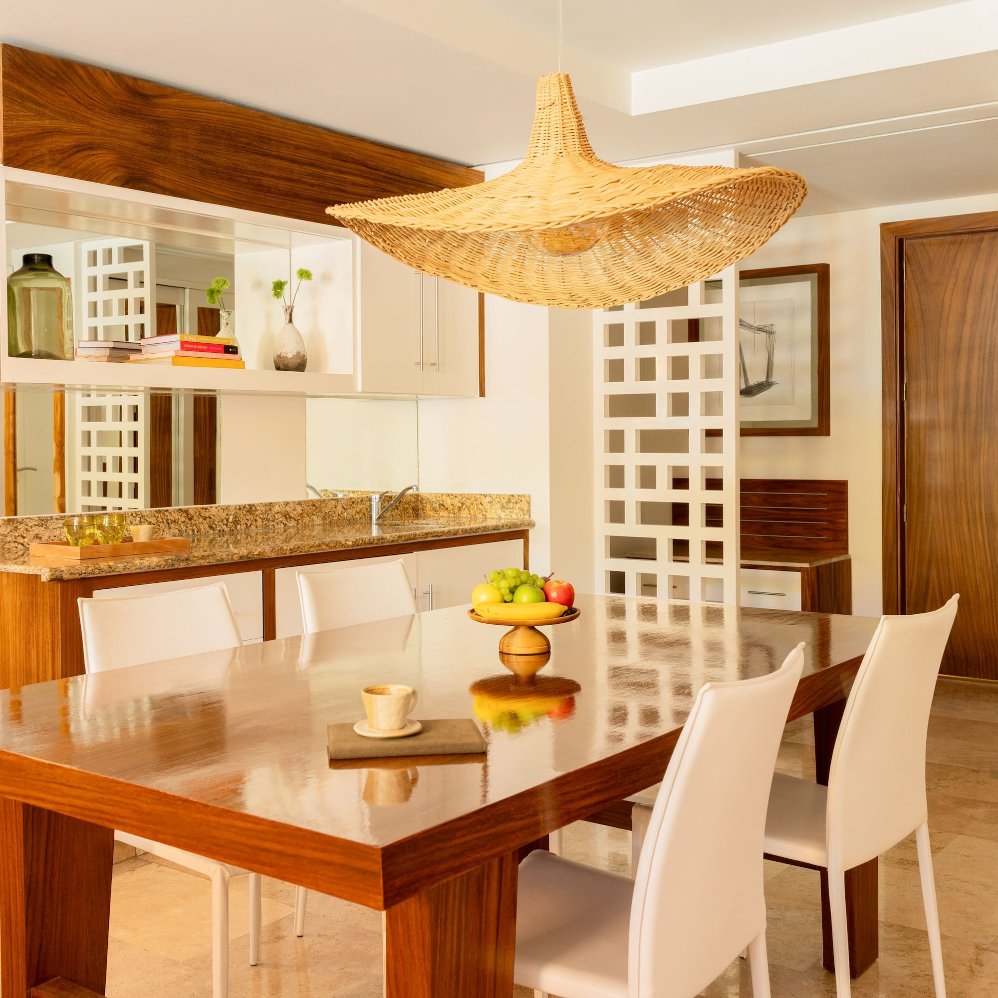 Modern dining room with wooden table, white chairs, and a wicker pendant light.