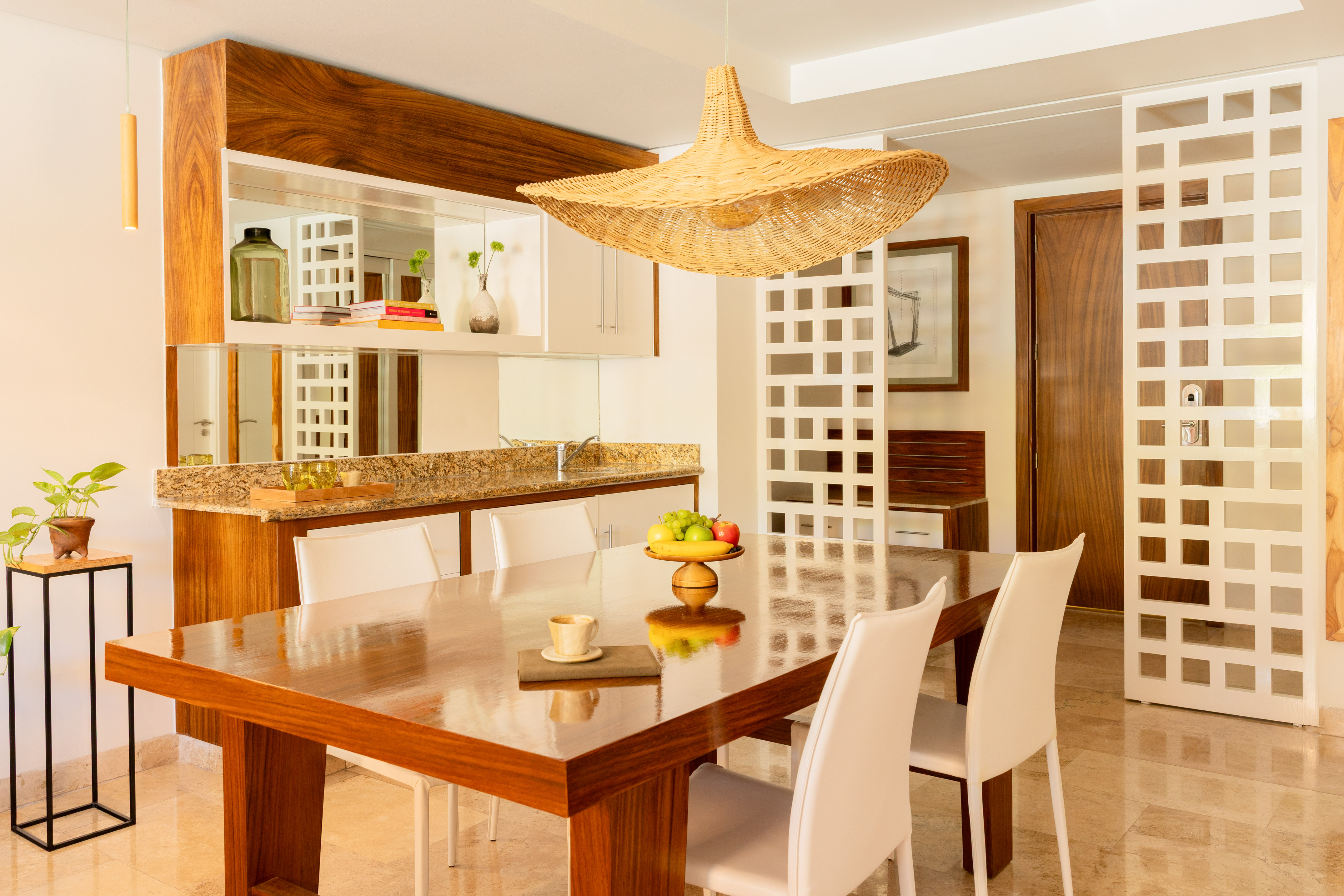 Modern dining room with wooden table, white chairs, and a wicker pendant light.