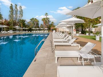 a pool with white chairs and umbrellas