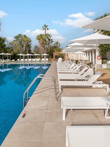 a pool with white chairs and umbrellas