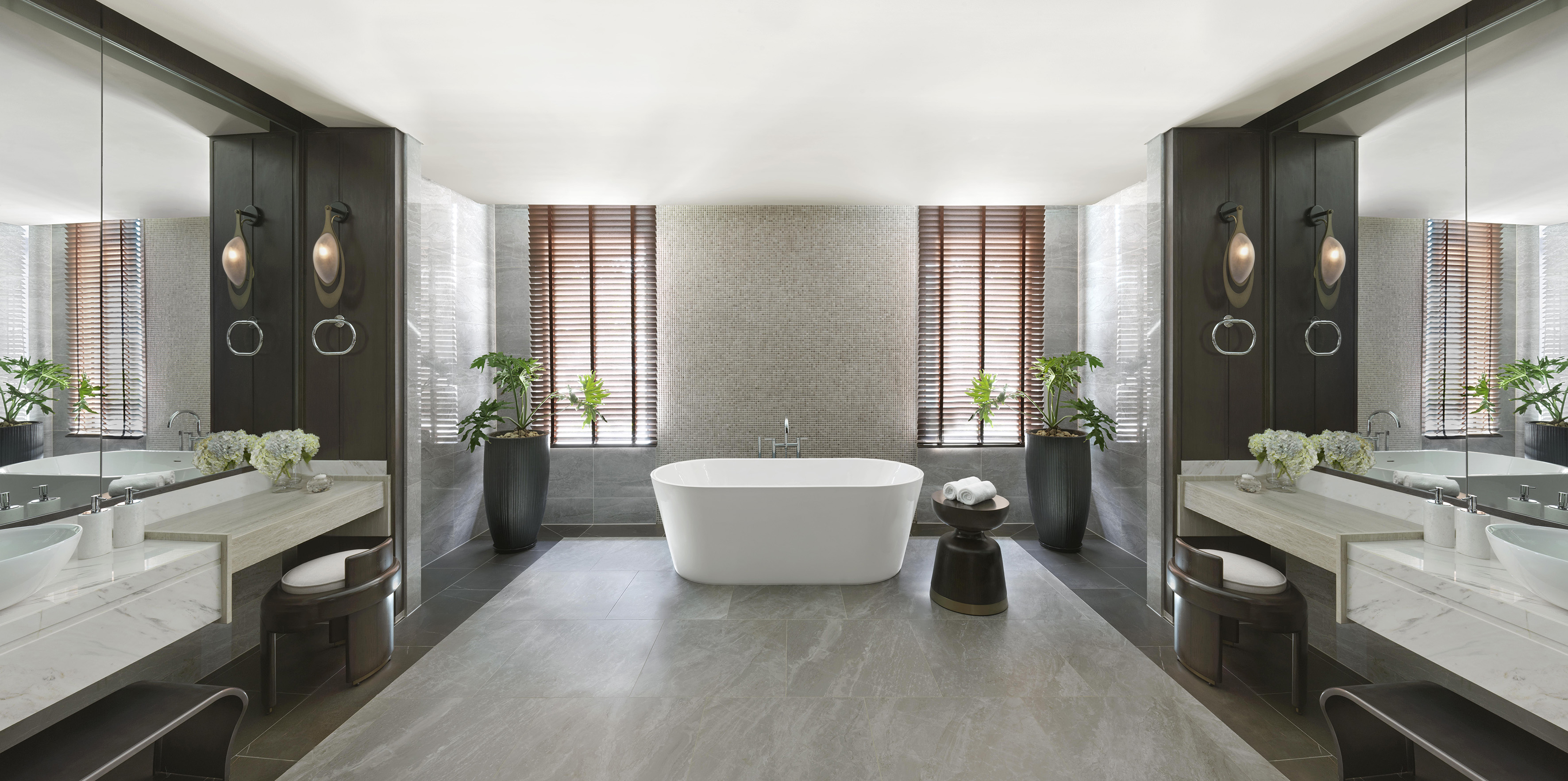 Modern luxury bathroom with freestanding bathtub, dual vanity, and plants.