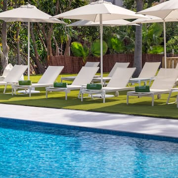 a pool with white chairs and umbrellas