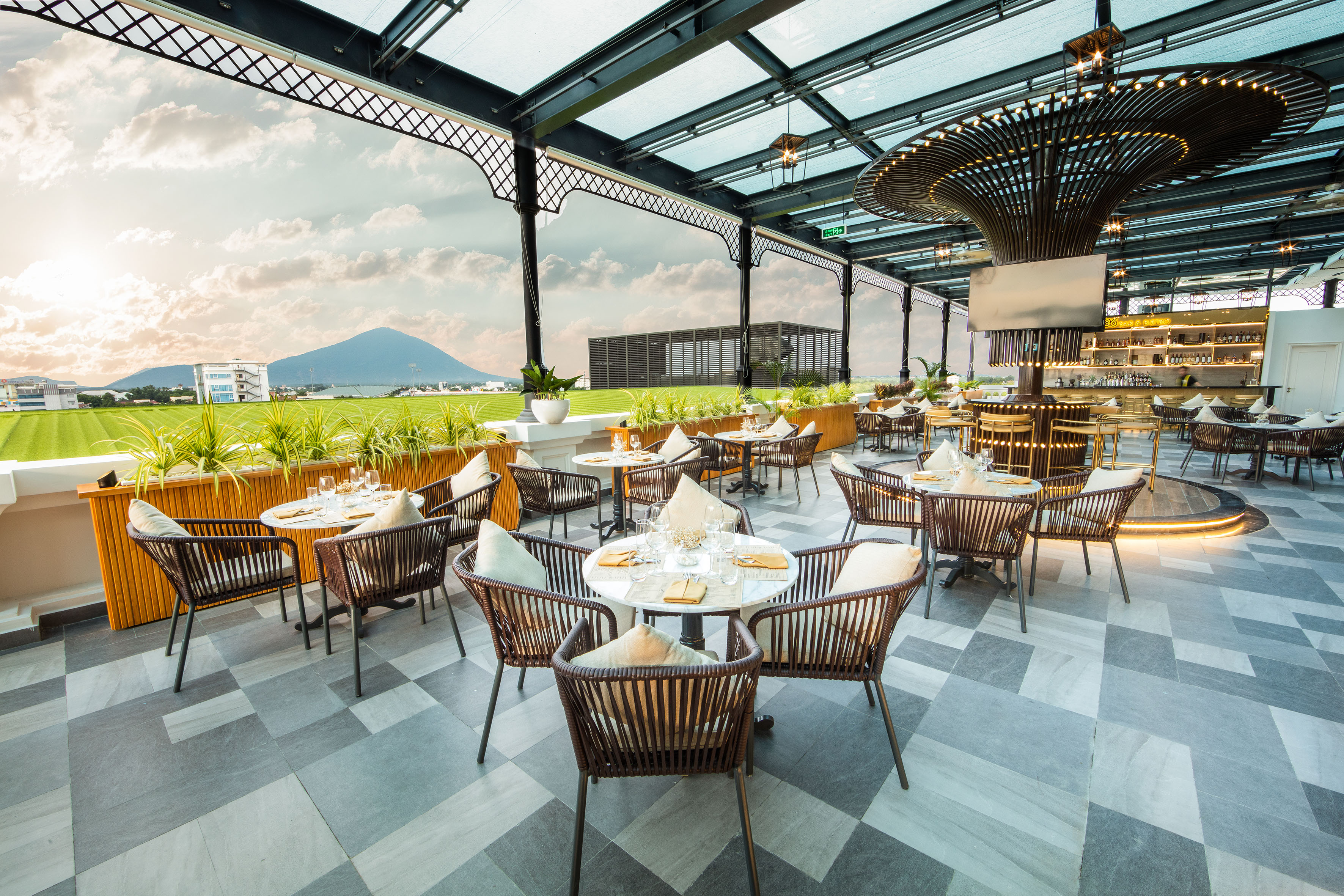 Modern rooftop dining terrace overlooking green fields and distant mountains.