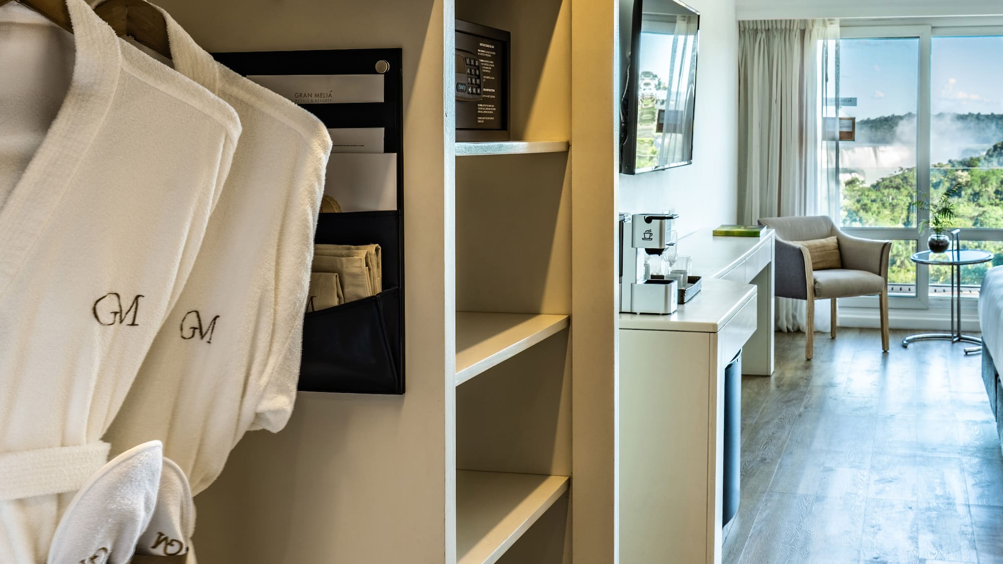 a room with white bathrobes and a bed and a television