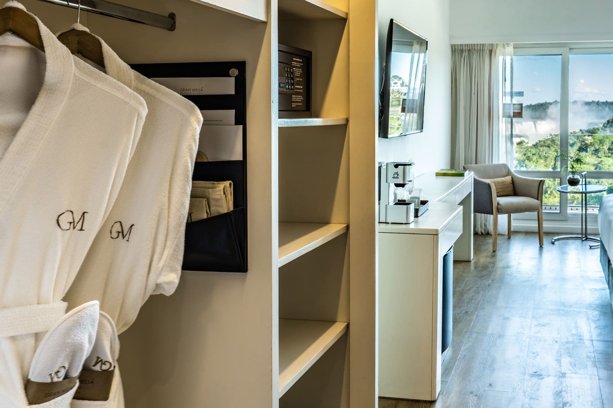 a room with white bathrobes and a bed and a television