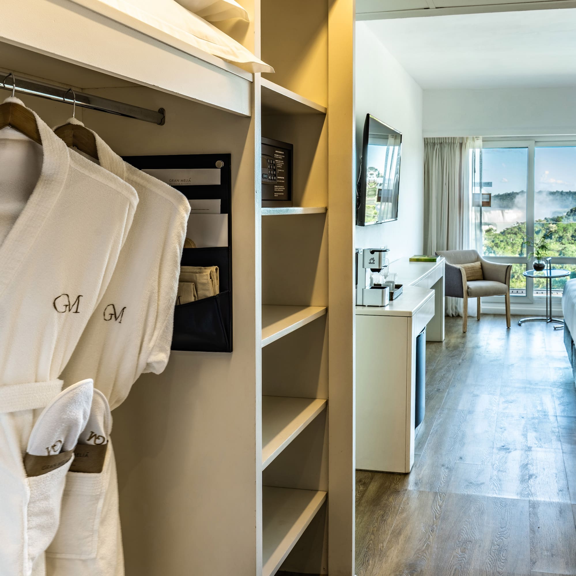 a room with white bathrobes and a bed and a television