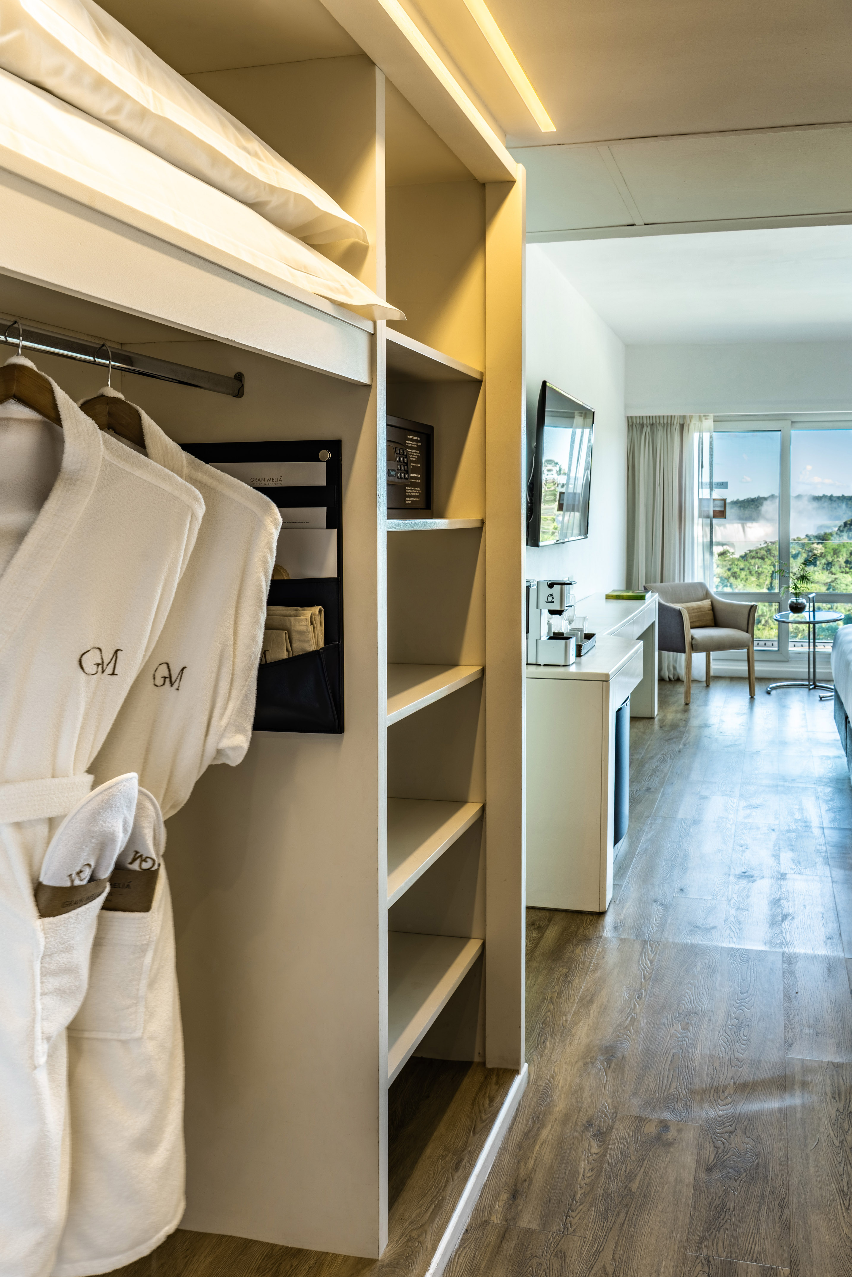 Hotel closet with bathrobes; luxury room, coffee maker, scenic waterfall view.